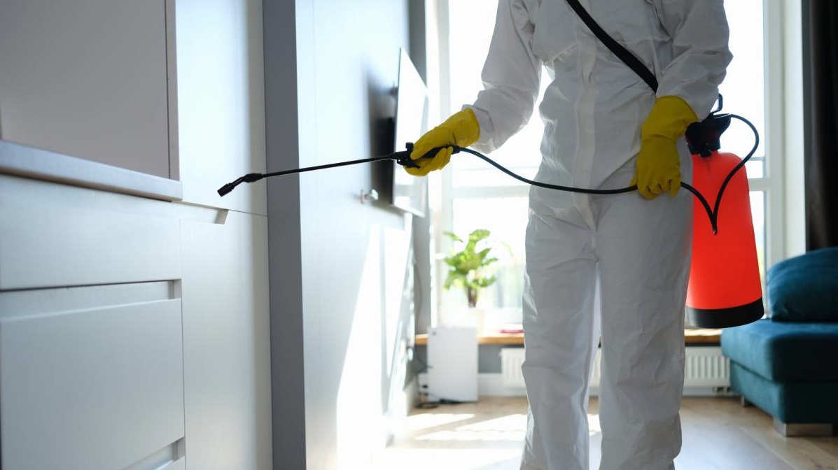 Técnico com EPI aplicando tratamento contra pragas em uma residência