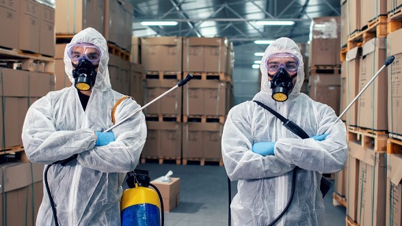 Profissionais com equipamento de proteção e pulverizadores